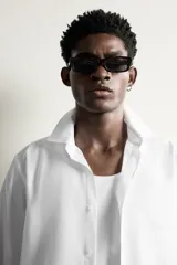Camisa de vestir blanca de corte slim fit, confeccionada en tejido de algodón con textura estructurada. Cuenta con cuello italiano, mangas largas con puños abotonados y cierre frontal con botonadura.