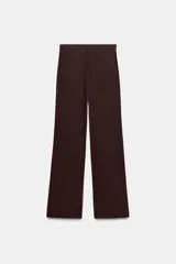 Pantalón negro de tiro alto, con trabillas, bolsillos laterales y de vivo en la espalda. Presenta pliegues en el delantero y cierre frontal con botón.