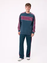 Sweater de cuello redondo marca Rusty, con diseño de bloques de color en azul marino y verde, con detalles de líneas blancas. Presenta el logo de la marca bordado en el pecho.