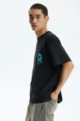 Remera de algodón negra de corte holgado, con cuello redondo y diseño gráfico de una flor celeste y la inscripción "Keep the wild alive" en el pecho.