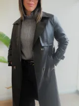 Trench de ecocuero negro con diseño cruzado de doble abotonadura, solapas clásicas, puños ajustables y largo midi.