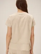 Camisa de manga corta color beige con estampado a cuadros, cuello en V y detalles de galones decorativos estilo oriental en la parte frontal.
