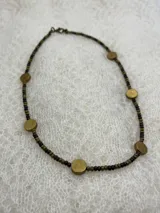 Gargantilla de cuentas pequeñas color marrón oscuro y apliques circulares dorados.