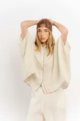 Camisa color crema de lino con mangas amplias y cinta en tono más oscuro en el cuello y la botonadura.