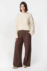 Sweater de punto color crudo con cuello alto y mangas largas abullonadas. Presenta apliques de cuero marrón en forma de rombos en los codos.