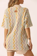 Vestido corto color crema con cuello tipo polo, mangas cortas y cierre delantero con botones. Diseño con patrón de zigzag en tonos celeste, naranja y lila.