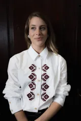 Camisa de algodón con corte clásico, cuello camisero y mangas largas con puños abotonados. Presenta un bordado geométrico en color bordó en la parte frontal y detalle de frunce en la espalda.