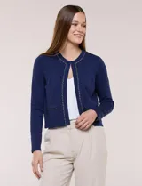 Cardigan corto azul marino de punto, con silueta entallada y largo a la cintura. Cuenta con un ribete decorativo que recorre el cuello redondo y la abertura frontal, integrando una cadena dorada en contraste. Posee bolsillos delanteros simulados y mangas largas.