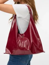 Cartera de hombro tipo hobo en color bordó con acabado efecto cuero craquelado. Presenta un diseño amplio con cierre de botón a presión central y una correa integrada al cuerpo de la cartera.