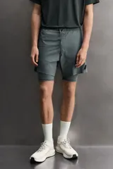 Pantalones cortos de entrenamiento 2 en 1 de Zara Athleticz, confeccionados en tejido técnico ligero y elástico. Presentan una malla interior integrada, cintura elástica con cordón ajustable, bolsillos laterales con cierre y aberturas en el bajo.