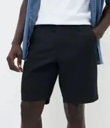 Bermuda masculina de corte slim confeccionada en sarga de algodón. Presenta un diseño de sastrería con cintura con trabillas, cierre tradicional y bolsillos laterales y traseros.