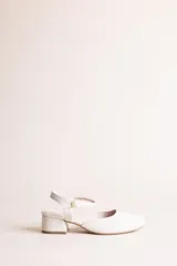 Zapato estilo Mary Jane confeccionado en cuero natural de color crudo, con puntera cuadrada, taco bloque de 4 cm y tira ajustable al tobillo con hebilla metálica dorada.