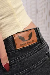 Pantalón wide leg de denim negro desgastado, de tiro medio con doble botón y corte amplio en las piernas con costuras frontales.