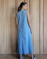 Vestido largo de denim azul, con escote en V, sin mangas, corte holgado, bolsillos laterales y aberturas en los costados de la falda.