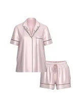 Pijama corto de satén color rosado con detalles de ribetes negros, compuesto por una camisa de manga corta abotonada con bolsillo en el pecho y el logotipo bordado en el cuello, y un short con cintura elástica.