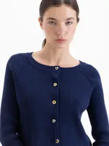 Cardigan de punto acanalado en color azul marino, con ajuste al cuerpo, mangas largas raglán y cierre frontal con botones dorados.