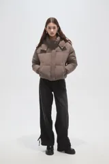 Campera puffer de corte corto y diseño acolchado, con cuello alto, capucha desmontable y cierre frontal oculto. Presenta puños elásticos y bolsillos laterales.