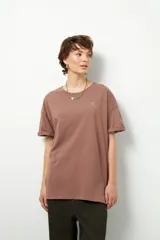 Remera negra de corte oversize con cuello redondo y manga corta. Presenta un pequeño estampado dorado en el pecho con la frase "love earth" y un símbolo de hojas.