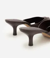 Sandalia mule Satinato de cuero marrón oscuro, con detalle de nudo frontal, taco kitten fino y puntera abierta.