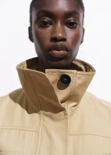 Chaleco oversize color beige, sin mangas, con cuello de solapa, cuatro bolsillos de parche con solapa en la parte delantera, fruncido elástico en la cintura y cierre frontal con botones.