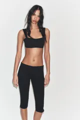 Pantalón capri de tiro medio confeccionado en tejido elástico, con cierre lateral mediante cremallera oculta.