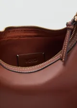 Cartera bandolera de efecto piel color marrón, con diseño semicircular, cierre de cremallera y asa de hebilla ajustable.