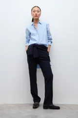 Camisa oversized de manga larga color celeste con rayas verticales finas en azul oscuro. Tiene cuello clásico y puños abotonados.