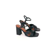 Sandalia de cuero color negro con tiras cruzadas en el frente, pulsera ajustable al tobillo con hebilla dorada y taco ancho alto. La punta es cuadrada y el interior está forrado en cuero.
