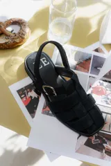 Sandalias de cuero marrón con diseño de tiras entretejidas y hebilla lateral.