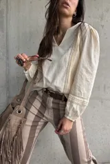 Blusa color manteca de manga larga con escote en V, detalles de encaje y bordados en las mangas.