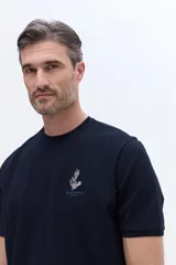 Remera de manga corta con textura, corte regular y cuello redondo. Presenta un diseño bordado en el pecho con motivos botánicos y el logo de la marca Brooksfield.