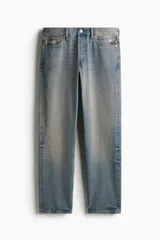 Jeans de cinco bolsillos en denim de algodón rígido, color celeste claro con efecto desgastado y decolorado. Modelo de cintura clásica con cierre de botón y corte relajado de cadera a bajo con pierna recta amplia.