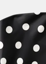 Vestido largo negro con estampado de lunares blancos, diseño asimétrico de un solo hombro y tejido fluido de poliéster. Incluye un fular a juego para el cuello.