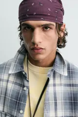 Camisa de algodón de corte relajado, con cuello solapa, manga larga terminada en puño con botón y dos bolsillos de plastrón con solapa en el pecho. Presenta un estampado de cuadros en tonos azules, grises y blancos, y cierre frontal de botonadura.