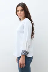 Remera blanca de manga larga con cuello redondo y puños con estampado de cuadros vichy en azul y blanco.