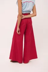 Pantalón de tiro alto, pierna ancha y largo, color beige claro con finas rayas verticales en tono oscuro. Presenta un diseño de cinco bolsillos estilo jean.