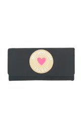 Billetera negra con cierre de solapa y broche a presión. Estampado frontal con parche redondo color beige con borde blanco y texto "SELF LOVE CLUB TRENDY" en negro y corazón rosa en el centro.