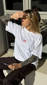 Remerón blanco de algodón con cuello redondo y mangas cortas. Estampado frontal con la frase "On my way to buy overpriced coffee" en letras rojas.