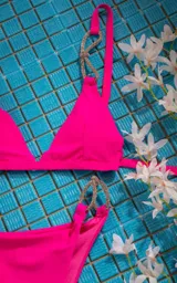 Conjunto de bikini fucsia con corpiño triangular y bombacha clásica con argollas plateadas con strass en los laterales.