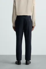 Pantalón chino de algodón color crema, corte regular fit, con cierre frontal de cremallera y botón, bolsillos delanteros y bolsillos traseros de vivo con botón.