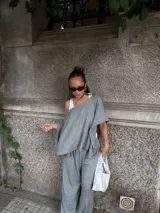 Blusa de lanilla gris con diseño asimétrico de un solo hombro y corte holgado tipo capa.