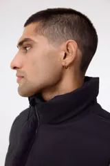 Chaleco acolchado de color negro, confeccionado en tejido guateado repelente al agua y rompevientos. Presenta un diseño con cuello elevado, cierre frontal completo con protección para el mentón y bolsillos laterales con cierre. Posee un corte estándar y está forrado internamente.
