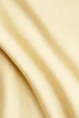 Buzo corto de punto fino suave color amarillo, con escote asimétrico y puños acanalados.