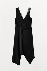 Vestido midi de viscosa color negro, sin mangas, con escote en pico adornado con encaje a tono. Presenta un detalle de nudo drapeado en la cintura y bajo asimétrico.