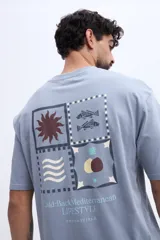 Remera oversize de manga corta color celeste, de corte relajado y amplio, confeccionada en algodón. Presenta un gran estampado en la espalda dividido en cuatro paneles con motivos gráficos (un sol, peces, ondas y formas abstractas) junto con inscripciones de la marca y estilo de vida.