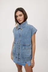 Chaleco de jean negro de calce relajado, con cuello camisero, cierre frontal con botones metálicos y bolsillos delanteros con solapa.