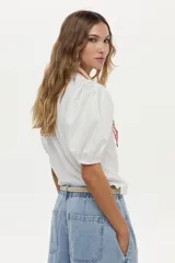 Blusa azul marino de algodón, con mangas abullonadas cortas de tela plana y gran bordado de rosa en tono crudo en el pecho.