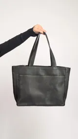 Cartera tipo shopper de cuero marrón texturado, con doble asa de hombro y un bolsillo frontal amplio con cierre de imán.