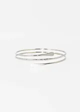 Brazalete plateado para el brazo, con diseño entrelazado doble y puntas redondeadas.