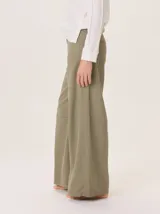 Pantalón ancho de algodón color verde oliva, con corte holgado desde la cadera hasta el tobillo. Presenta pinzas debajo de la rodilla, bordado de monograma en el bolsillo delantero y pespuntes a contratono.